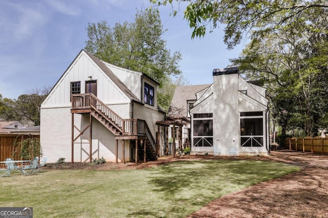 rear view of house featuring a chimney, stairway, brick siding, a sunroom, and fence