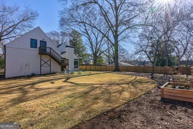 view of yard featuring a vegetable garden, fence, and stairs