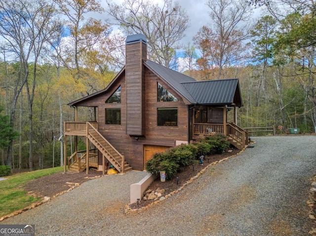 view of front of home featuring a porch, a chimney, metal roof, and fence