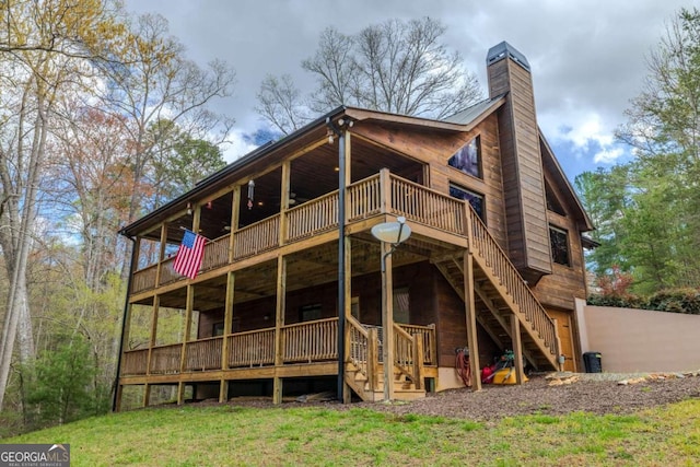 rear view of property with a wooden deck, a chimney, and stairs