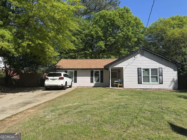 ranch-style house featuring concrete driveway, fence, and a front lawn
