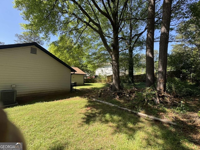 view of yard with central air condition unit and fence
