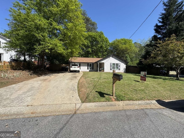 ranch-style home with concrete driveway, fence, and a front lawn