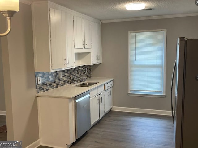 kitchen featuring a sink, light countertops, appliances with stainless steel finishes, wood finished floors, and backsplash