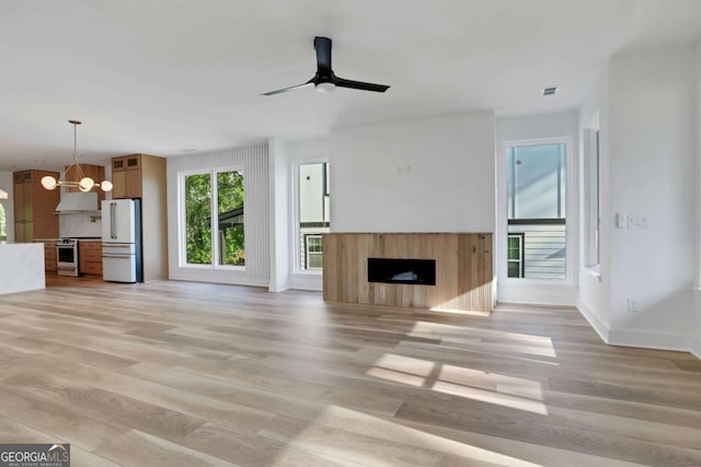 644 Glendale Rd, Scottdale, GA 30079 - unfurnished living room featuring ceiling fan with notable chandelier, light wood-style flooring, a fireplace, baseboards, and visible vents