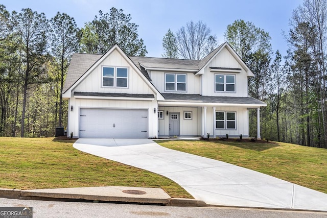 view of front facade with a front yard, a shingled roof, an attached garage, board and batten siding, and driveway