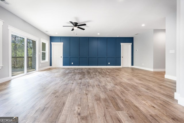 unfurnished living room with a decorative wall, visible vents, a ceiling fan, and light wood-style floors