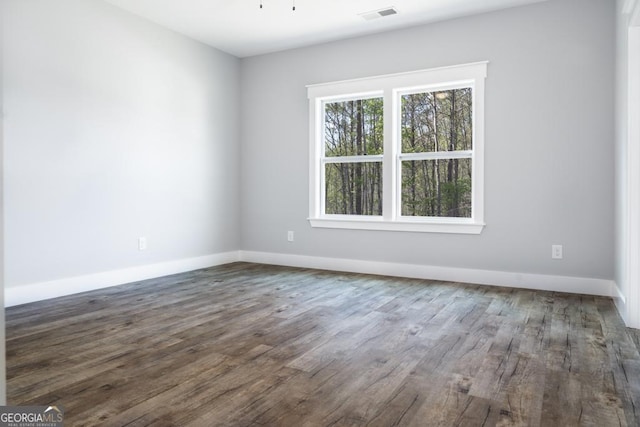 spare room featuring baseboards, dark wood-style floors, and visible vents