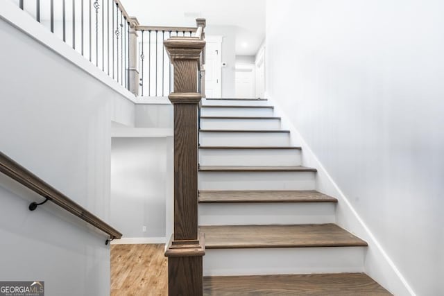 stairway with a high ceiling, baseboards, and wood finished floors