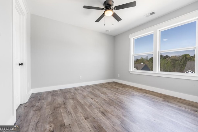 spare room with visible vents, baseboards, a ceiling fan, and wood finished floors