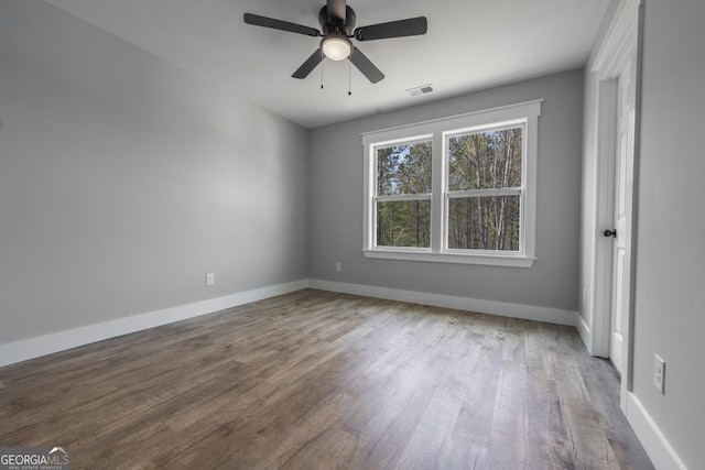 spare room with visible vents, ceiling fan, baseboards, and wood finished floors