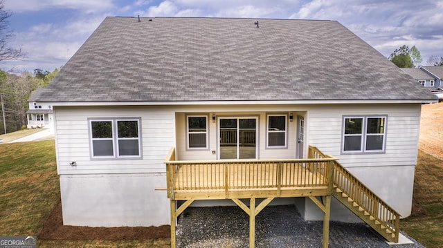back of property with a shingled roof, a lawn, a deck, and stairs