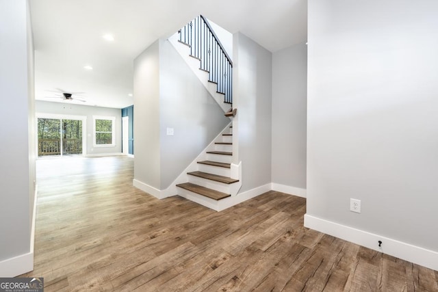 stairway with wood finished floors, baseboards, a ceiling fan, and recessed lighting