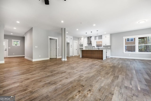 unfurnished living room featuring wood finished floors, baseboards, a ceiling fan, and recessed lighting