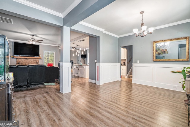 living room with wood finished floors, visible vents, ornamental molding, and ceiling fan with notable chandelier