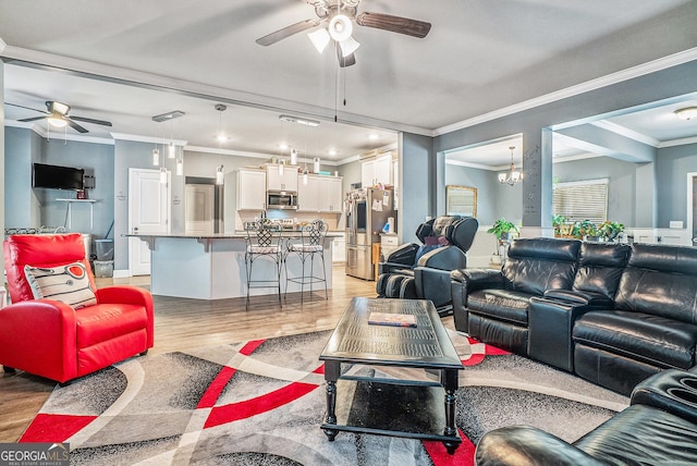 living room with light wood-type flooring, crown molding, and ceiling fan with notable chandelier