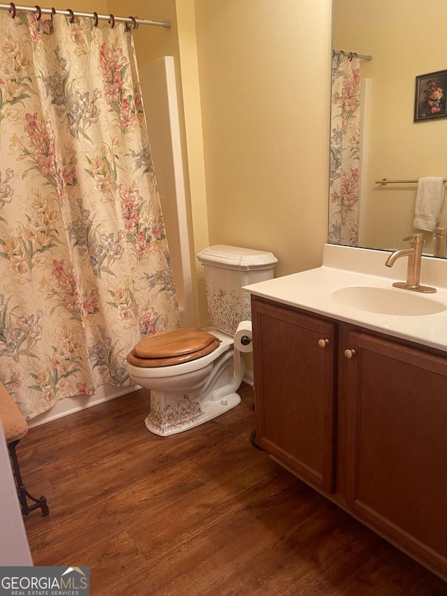 bathroom with toilet, shower / bath combo with shower curtain, vanity, and wood finished floors