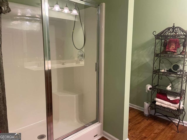 full bathroom with baseboards, a stall shower, and wood finished floors
