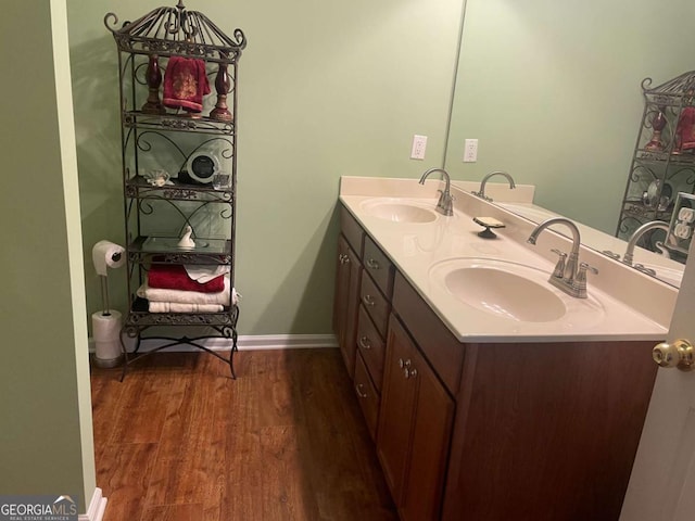 bathroom with a sink, baseboards, double vanity, and wood finished floors