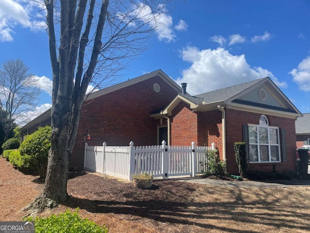 ranch-style home featuring brick siding and fence
