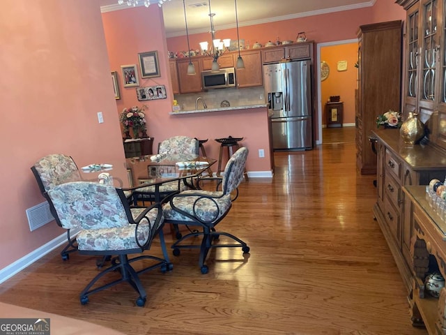 dining area with visible vents, baseboards, ornamental molding, and wood finished floors