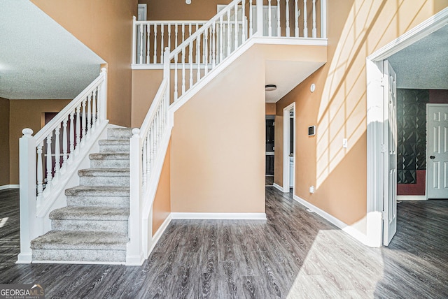4180 W Stubbs Rd, College Park, GA 30349 - staircase featuring baseboards, a towering ceiling, and wood finished floors