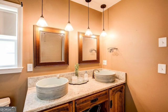 bathroom featuring toilet, double vanity, and a sink