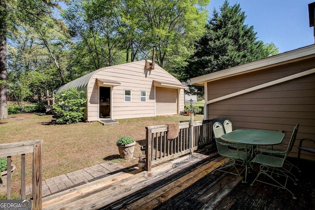 deck featuring an outdoor structure, outdoor dining area, and a lawn
