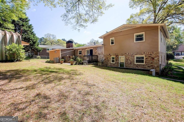 rear view of house with central AC, a deck, a lawn, fence, and brick siding