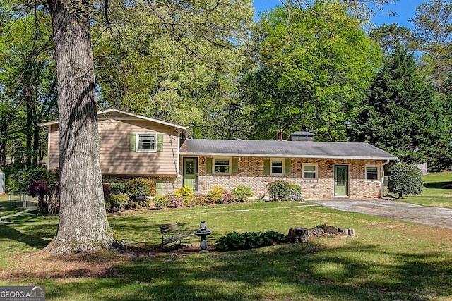 split level home featuring a front yard and brick siding