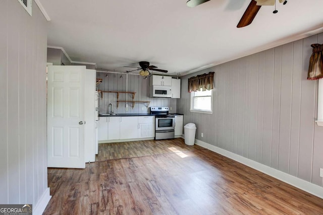 kitchen featuring white microwave, dark countertops, stainless steel range with electric cooktop, ceiling fan, and wood finished floors