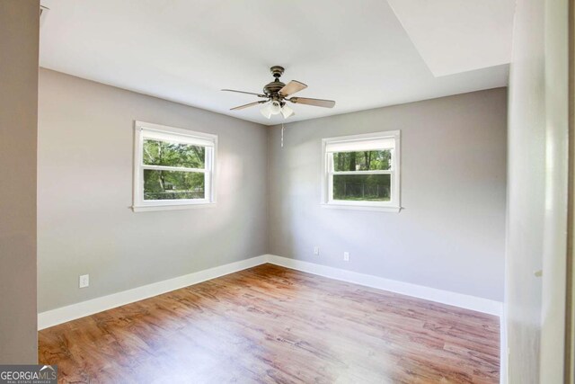 spare room with wood finished floors, baseboards, and a ceiling fan