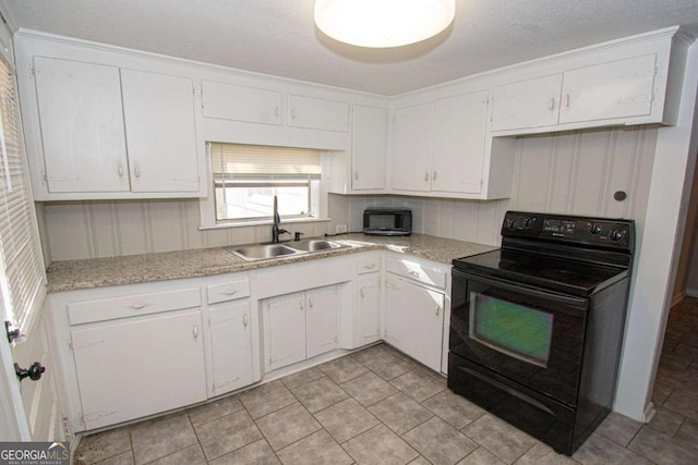 226 Vine St, Athens, GA 30601 - kitchen with black electric range, white cabinets, and light tile patterned floors