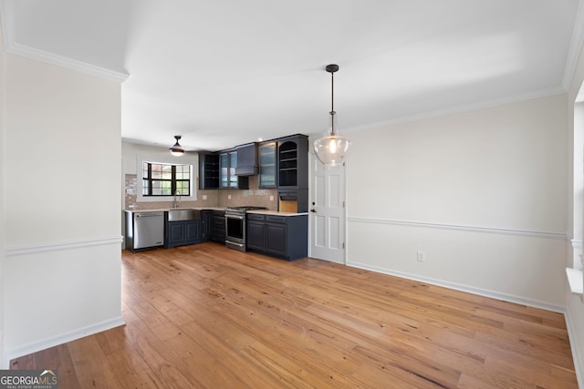 kitchen with light wood-style flooring, ornamental molding, light countertops, stainless steel appliances, and decorative backsplash