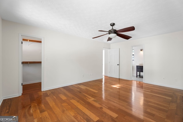 interior space featuring a textured ceiling, baseboards, wood finished floors, and ceiling fan