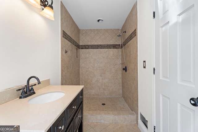 full bathroom featuring tiled shower and vanity