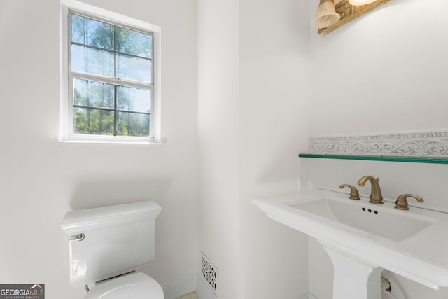 half bath with visible vents, a sink, and toilet
