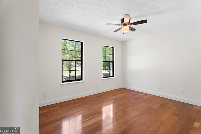 empty room with a ceiling fan, wood finished floors, and a textured ceiling