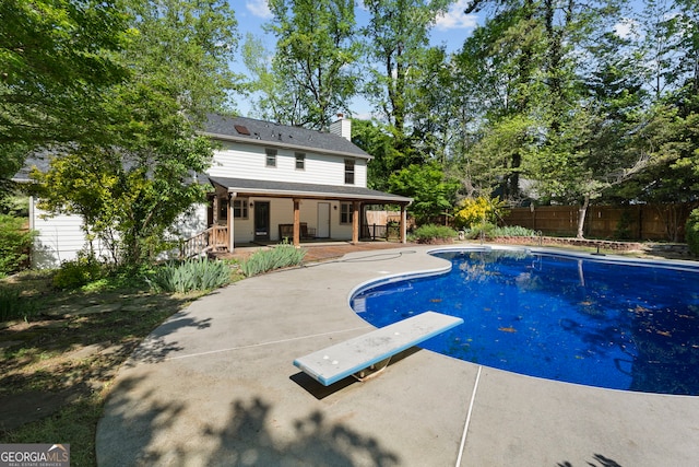 view of pool featuring a patio area, fence, a fenced in pool, and a diving board