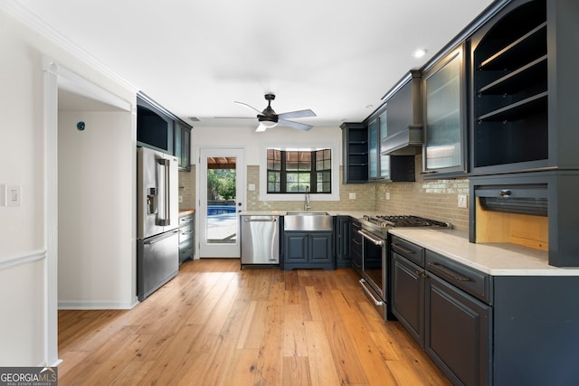 kitchen featuring tasteful backsplash, a sink, ceiling fan, stainless steel appliances, and light wood-style flooring