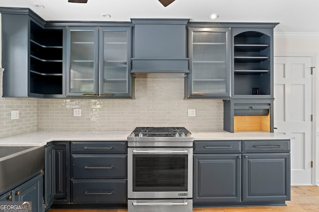 kitchen featuring stainless steel gas range, light countertops, open shelves, and decorative backsplash