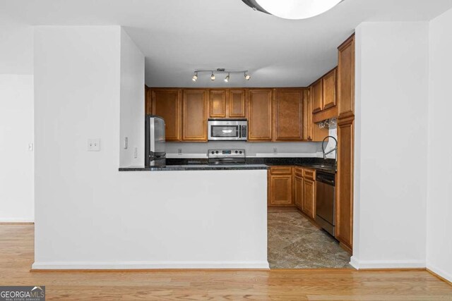 1468 Briarwood Rd NE Unit 602, Atlanta, GA 30319 - kitchen with brown cabinets, dark countertops, light wood finished floors, and stainless steel appliances