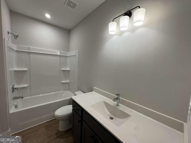 bathroom with visible vents, toilet,  shower combination, vanity, and wood finished floors