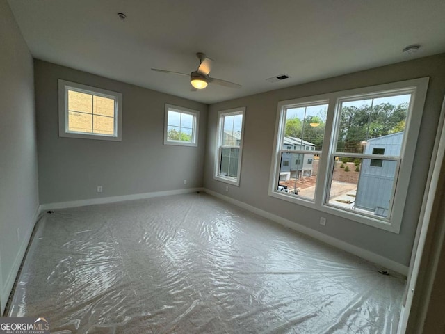 unfurnished room with baseboards, a ceiling fan, and visible vents
