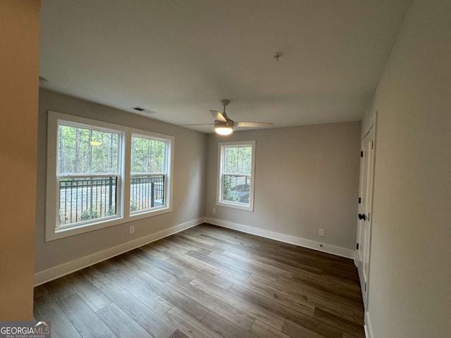 unfurnished room with dark wood-style floors, baseboards, a ceiling fan, and visible vents