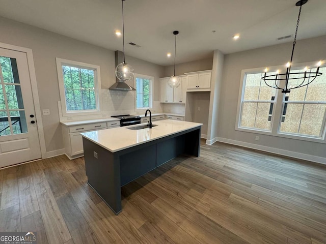 kitchen featuring wall chimney exhaust hood, white cabinetry, light countertops, a sink, and dark wood-style floors