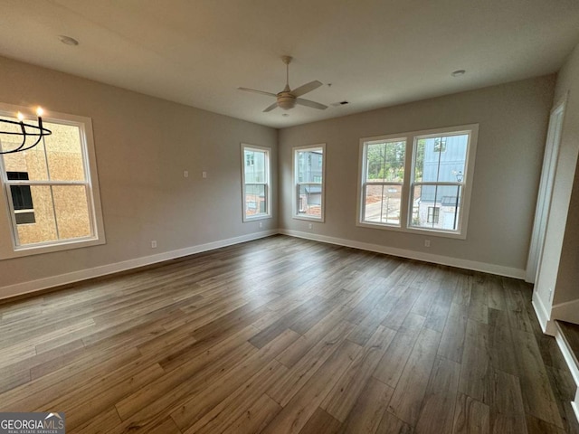 interior space featuring dark wood-style flooring, baseboards, and ceiling fan with notable chandelier