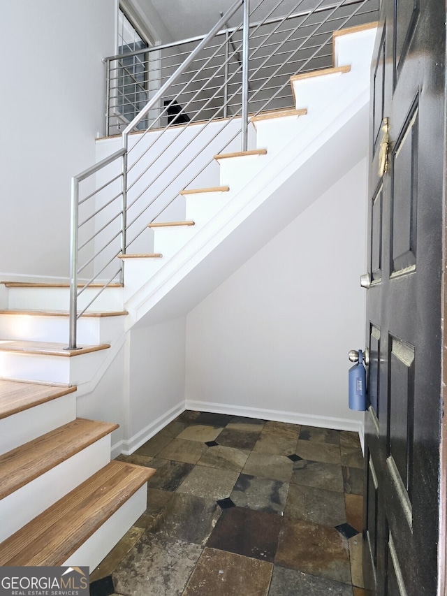 staircase featuring baseboards and stone finish flooring