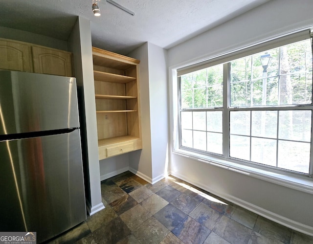 interior space featuring a textured ceiling, a healthy amount of sunlight, baseboards, and stone tile floors