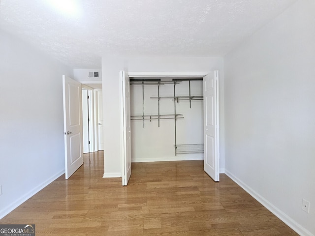 unfurnished bedroom featuring light wood-style floors, a closet, baseboards, and visible vents